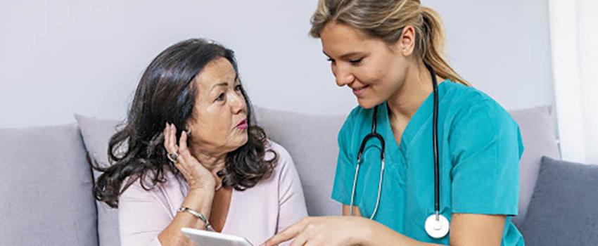 Healthcare worker with stethoscope talking to Spanish woman.