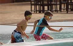 Two boys running in pool with goggles on.